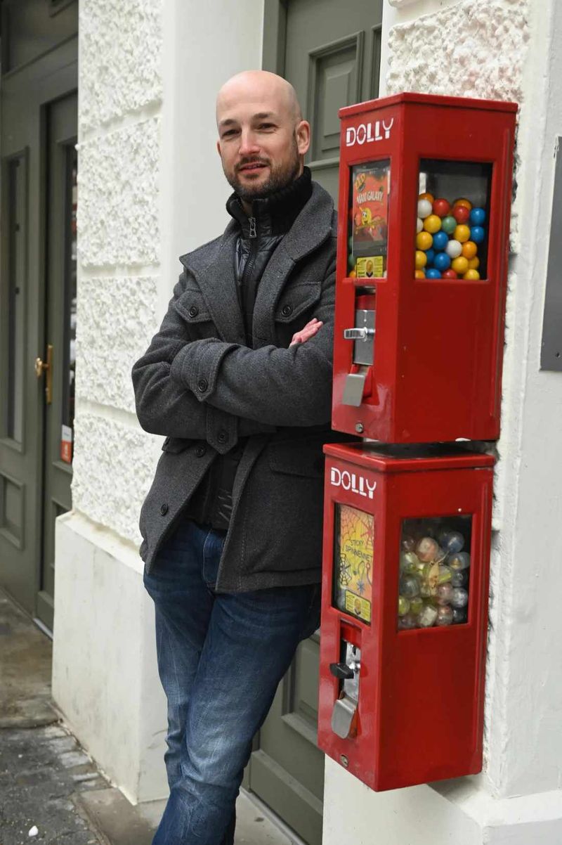 Geschäftsführer Hannes Viehhauser neben zwei übereinander montierten roten Kaugummiautomaten