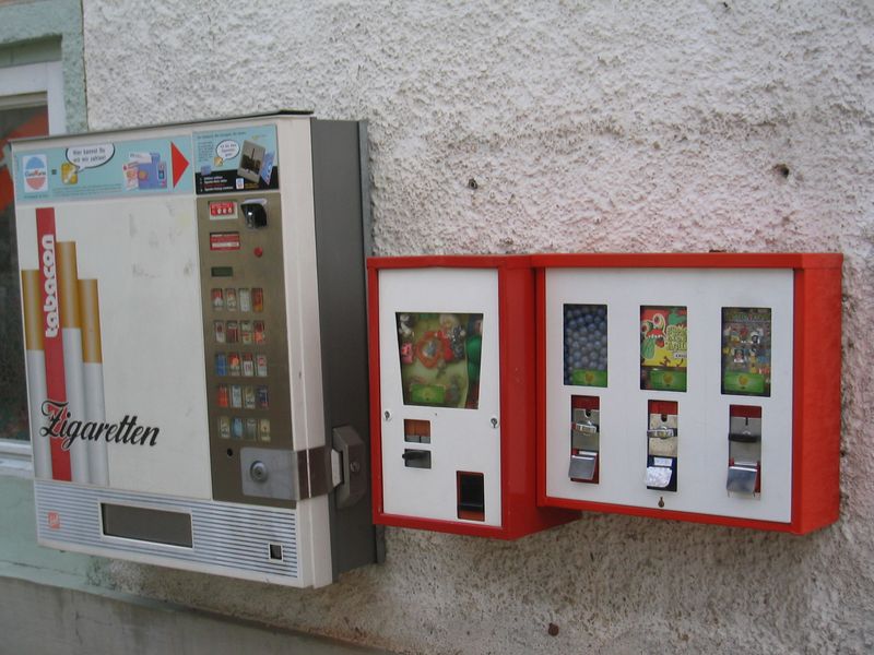 Rot-weißer Doppelautomat neben einem Zigarettenautomaten an einer Hauswand