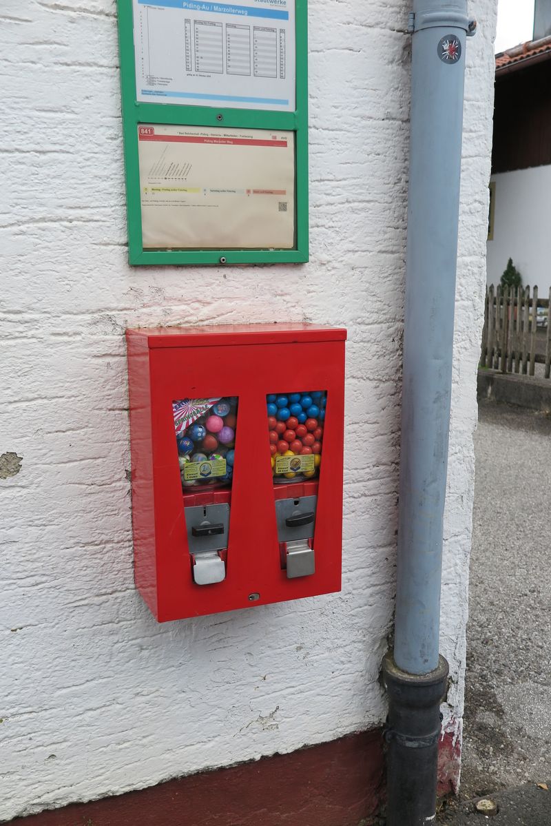 Roter Doppelautomat mit bunten Kaugummikugeln neben einem Fallrohr