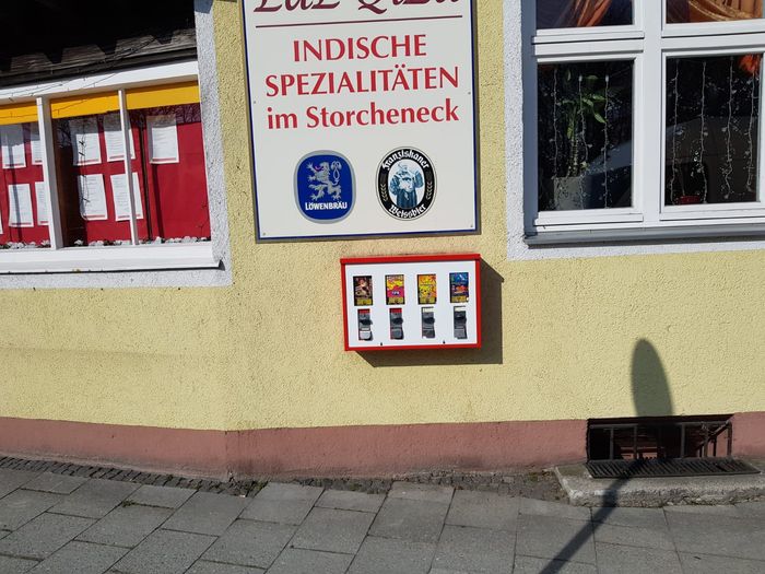 Rot-weißer Dreifach-Automat unter dem Schild eines Restaurants