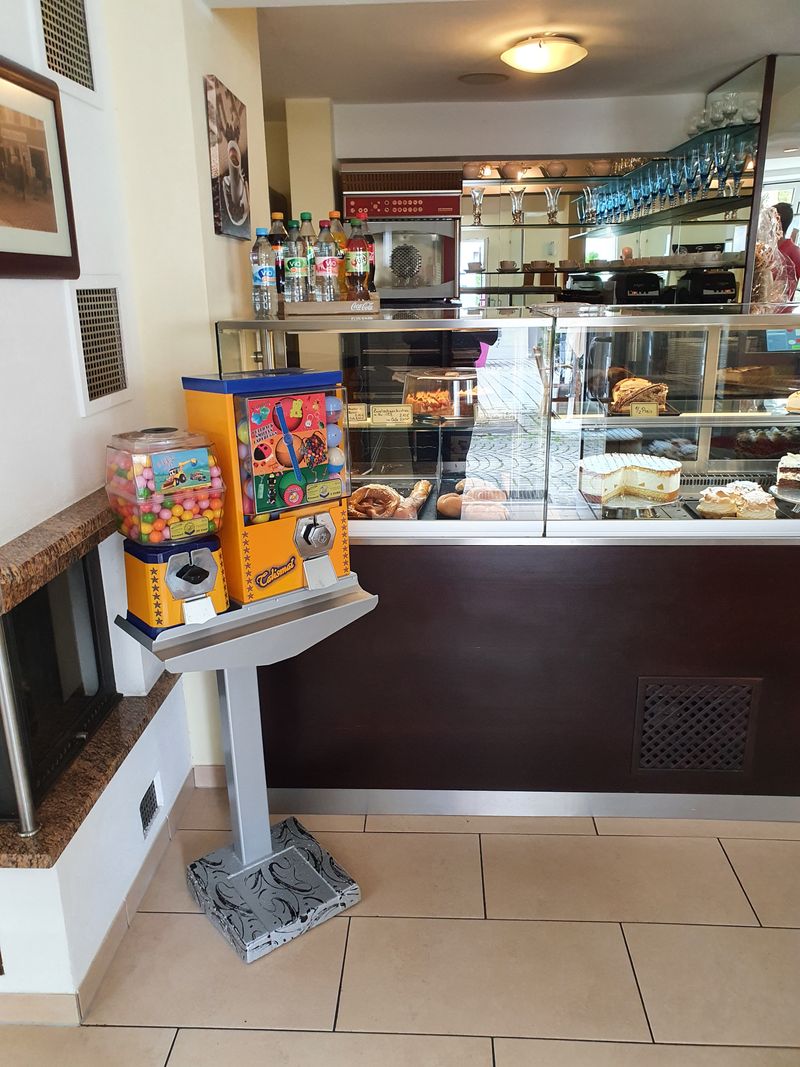Gelber Talismat und Kaugummiautomat auf einem Ständer in einem Café