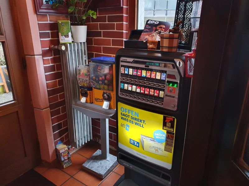 Talismat-Ständer neben einem Spielautomaten in einer Gaststätte