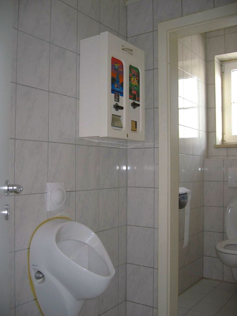 Weißer Kondomautomat an der Wand einer Herrentoilette