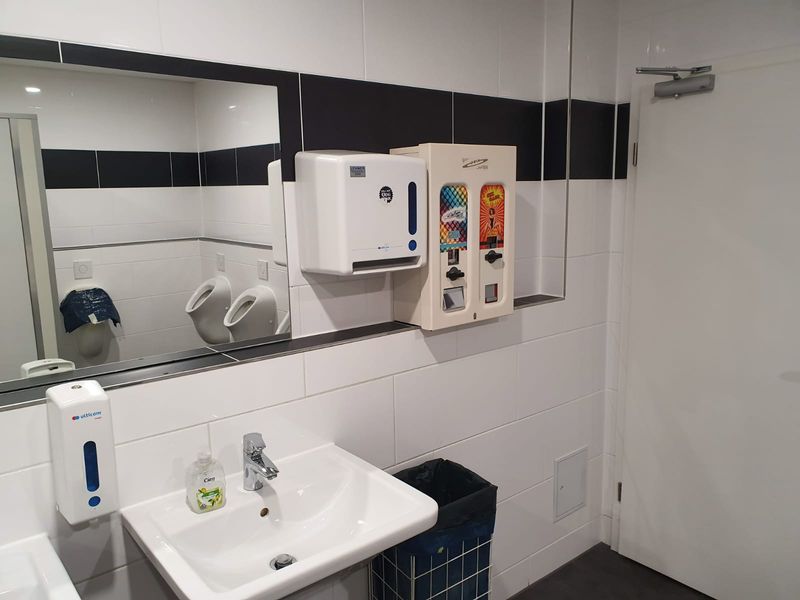 Kondomautomat neben einem Handtuchspender in einem modernen Waschraum